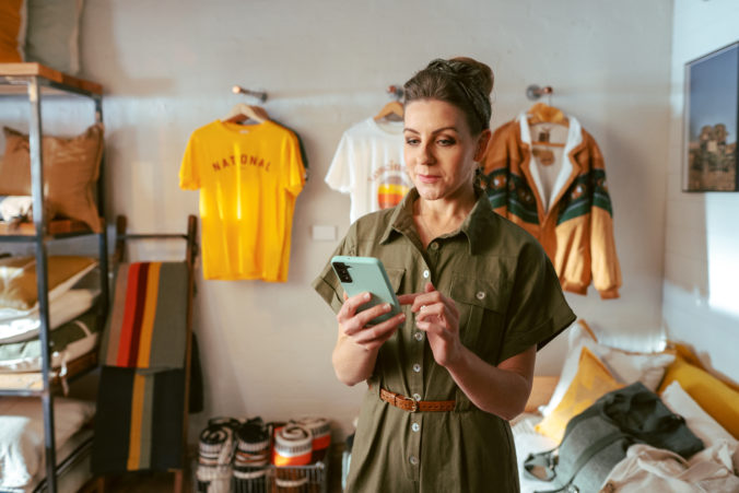 Tyro-woman-holding-smartphone-in-clothing-store